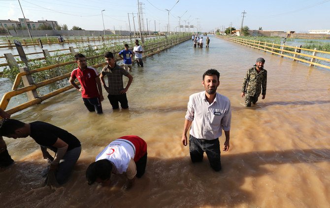 イランのフーゼスタン州の州都アフヴァーズ市で、冠水した道路に水を封じ込めるためのバリケードを設置している。2019年4月10日。(AFP/ファイルフォト)