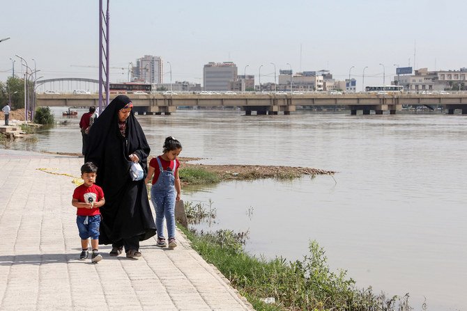 イラン南西部にあるフーゼスタン州の州都アフヴァーズ市で、堤防が決壊したカールーン川沿いを子供たちと歩く女性。2019年4月11日。(AFP/ファイルフォト)