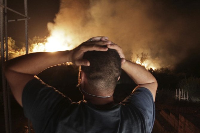 2021年8月11日（水）、アルジェの東100キロに位置するティジウズー近郊のラルバ・ナス・イラテン村の近くで発生した山火事を見る男性。（AP）