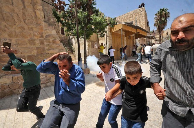 2021年8月13日、イスラエルの占領下にあるヨルダン川西岸地区のイブラヒミモスクでの金曜礼拝後に起きたデモ隊とイスラエルの治安部隊との衝突の中、催涙ガスを避けようと走るパレスチナ人礼拝者たち。（AFP）