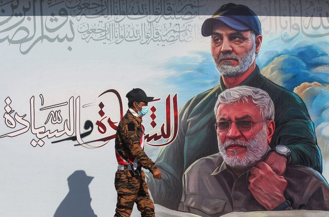 バグダッドで、イラクの故アブ・マフディ・アル・ムハンディス司令官（右）とイランのIRGC司令官ガーセム・ソレイマニ氏を描いたポスターの前を通るハシュドの戦闘員。（AFP通信）