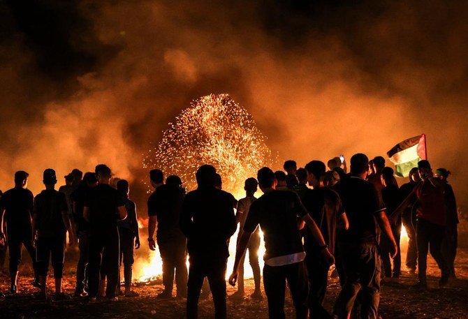 2021年8月28日、ガザ市東部にあるガザ地区とイスラエルの境界付近で抗議デモを行い、タイヤを燃やすパレスチナ人のデモ参加者。(AFP)