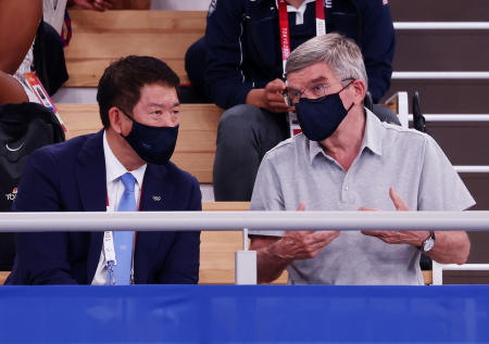 防護フェースマスクを着用して観客席に座っている国際オリンピック委員会のトーマス・バッハ会長（右）。（ロイター）