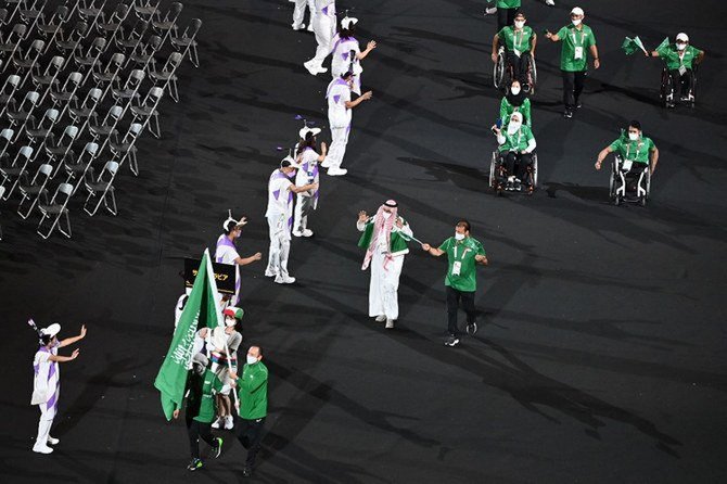 東京2020パラリンピック競技大会の開会式でサウジアラビアの国旗を掲げるサラ・ジュマーハ選手とアハメド・シャルバトリ選手。(AFP)