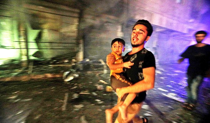 政府軍による爆撃の直後、子供を抱きかかえながら安全な場所を求めて奔走する男性。金曜日未明、シリア北部のアレッポ北西に位置する、反政府勢力が掌握する都市アル＝バーブにて。（AFP）