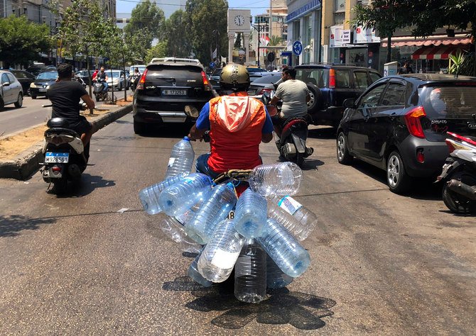 2021年6月23日、レバノンのベイルートで、ガソリンを入れる空の水筒を持ってスクーターに乗る男性。（AP）