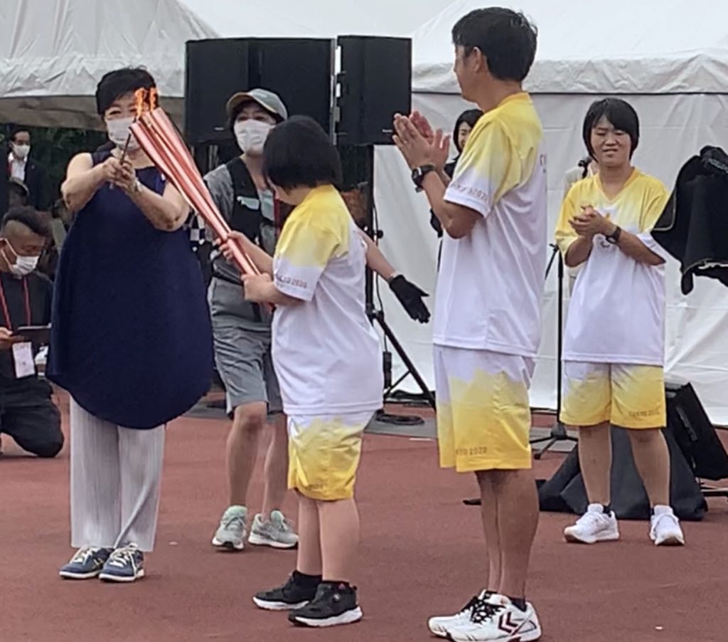 2021年8月22日日曜日、2020夏季パラリンピックを前に日本の航空自衛隊のブルーインパルスが練習を行う中、東京の国立競技場付近に集まる人々。（共同通信、AP通信経由）
