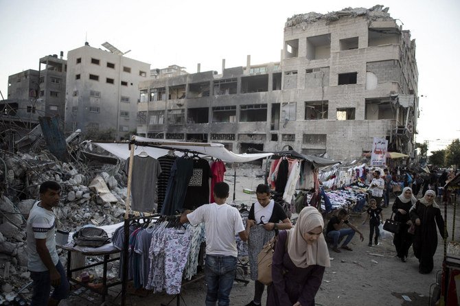 11日間にわたるガザのハマスとイスラエルの戦闘中にイスラエル軍の空爆によって破壊された建物の横で、パレスチナ人の露天商が衣服を販売している。イスラエルは火曜日、多数のトラックによる建設資材のガザ地区への搬入を許可した。（AP通信）