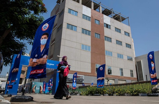 2021年9月1日、首都カイロで、中国シノバック社の新型コロナウイルスワクチンのバイアルが製造されているエジプト企業ワクセラ社の前を歩く女性。(AFP)