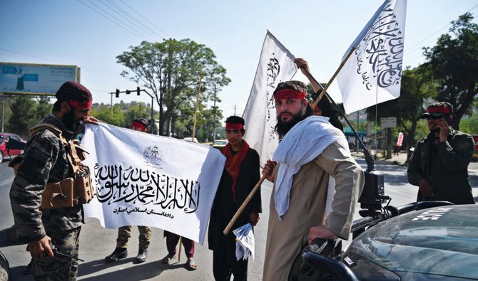 アフガニスタンの首都カブールの道路沿いで見張りをしながら旗を振るタリバンの戦闘員たち。タリバンは安全上の理由から抗議活動を禁止した。(AFP)