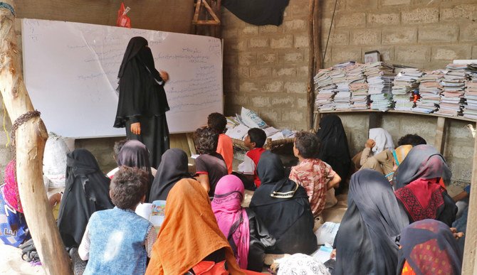 2021年9月1日、南部ホデイダ県の農村地域ムヒブにある自宅の床いっぱいに座る子どもたちに授業を行うイエメンの教師アミナ・マハディ氏（左）。（AFP通信）