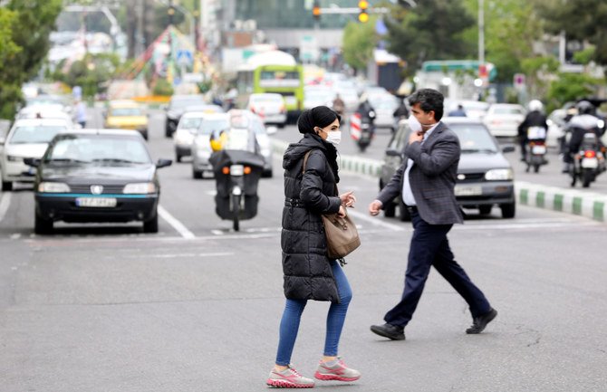 コロナ禍でマスクを着けたイランの人々がテヘランの大通りを横切っていく。（AFP資料写真）