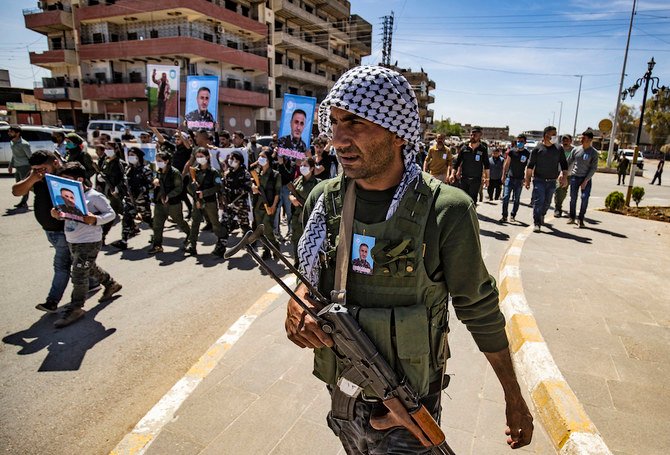 殉職した同志ハリド・ハジの遺体を前に行進するシリアのクルド人治安部隊「アサイッシュ」のメンバー。（AFP/ファイル・写真）