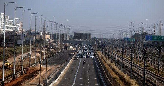 イスラエルのテルアビブにて2021年10月31日、新型コロナウイルス感染が発生する中、「グリーンパス」の制限に関する政府の新たな方針に抗議するため、テルアビブの入り口付近の高速道路で行き交う車両を減速させるため、人々が車列を組んで運転している。（ロイター通信）