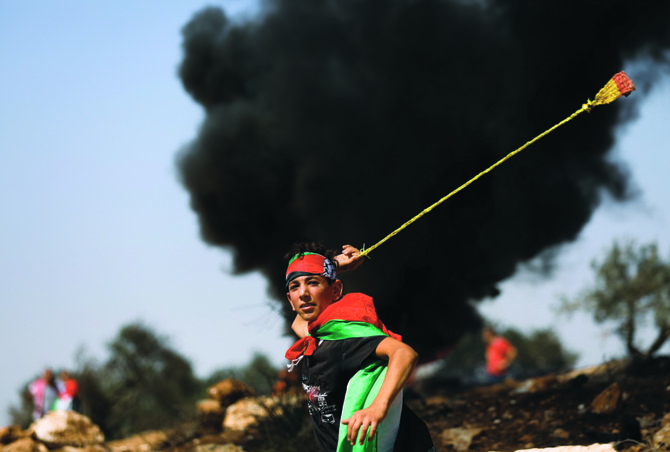 イスラエルの入植に対する抗議デモで投石器を使用するパレスチナ人のデモ参加者（イスラエル占領下のヨルダン川西岸、ベイタにて金曜日撮影）。 （ロイター）