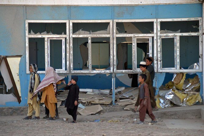 2021年10月14日に撮影されたこの画像ではアフガン人の子供がアルガンダブ地区バブロ村にある銃痕が残る学校の脇を歩いている。（AFP）