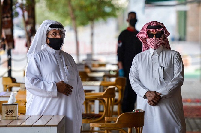 カフェでマスクをしてテーブルの消毒を待つ客。2020年6月21日、サウジアラビアの首都リヤドで。（ファイル/AFP）