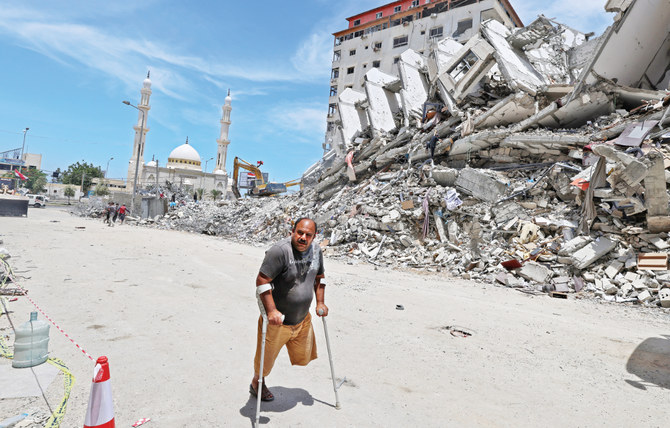 5月、ガザ市でイスラエル軍の空爆により破壊された建物の瓦礫の前を歩く身体の不自由なパレスチナ人男性。ガザ市の再建には数十億円が必要となる。(写真/AFP)