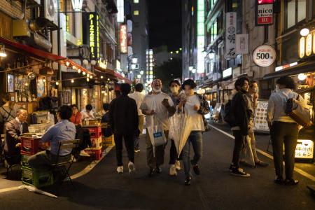 2021年10月1日(金)、政府がコロナウイルスの非常事態を解除した最初の夜、東京のレストランやバーで他の人が飲食する中、人々は路上でたむろしています。(AP)