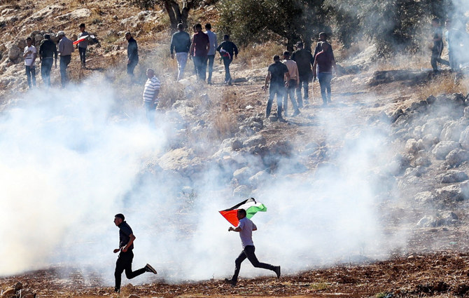 ヨルダン川西岸地区にあるナブルスの東に位置するベイト・ダジャンで5日に行われたデモで、イスラエルの治安部隊が発射した催涙ガスから逃げ惑うパレスチナのデモ隊。（AFP通信）