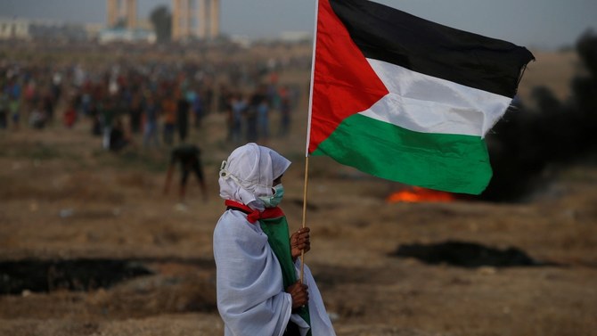 2018年10月19日、ガザのイスラエル・ガザ国境フェンスでの抗議活動で、パレスチナの旗を掲げる女性。（ロイター）