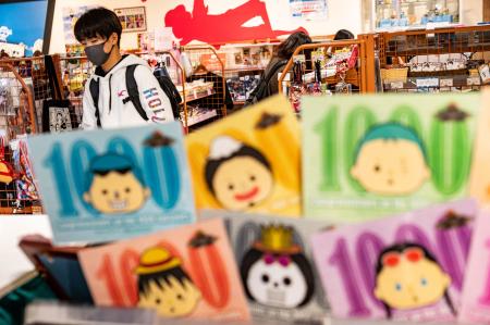 東京のお土産店でアニメ『ONE PIECE』の1000回放送を祝うカードの後ろを歩く男性。2021年11月19日撮影。(AFP)