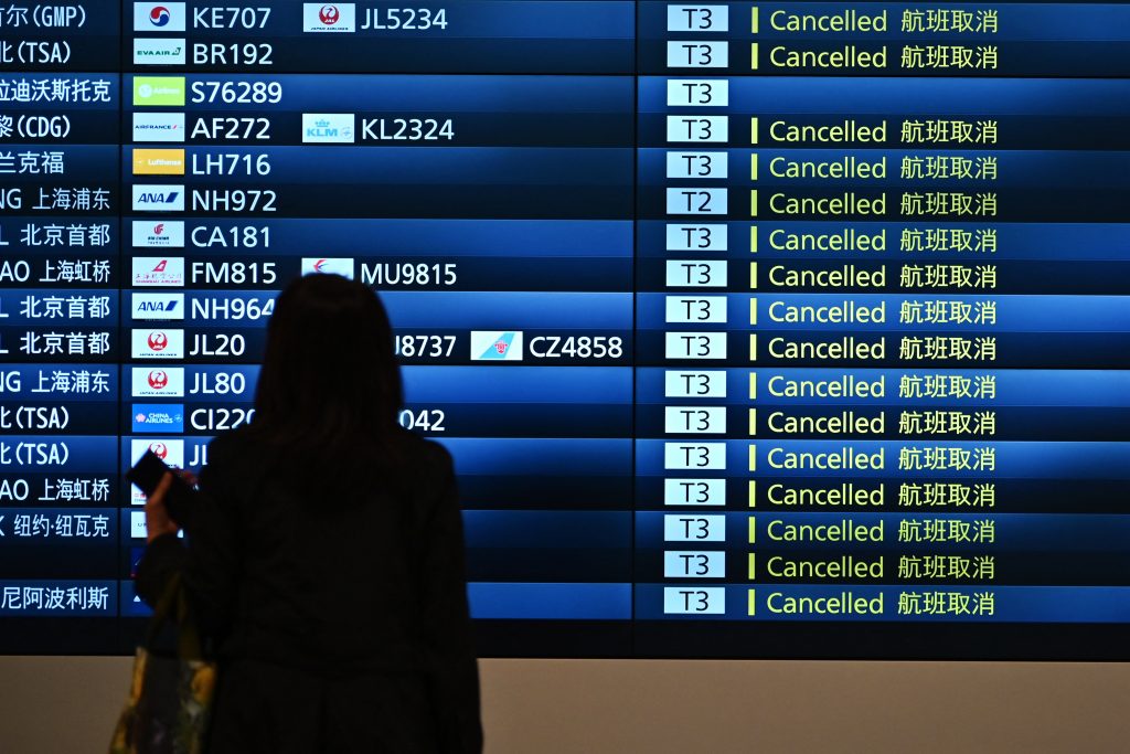 東京の羽田空港国際線旅客ターミナルの到着フロアで、欠航便の掲示板を見る女性。（AFP通信）