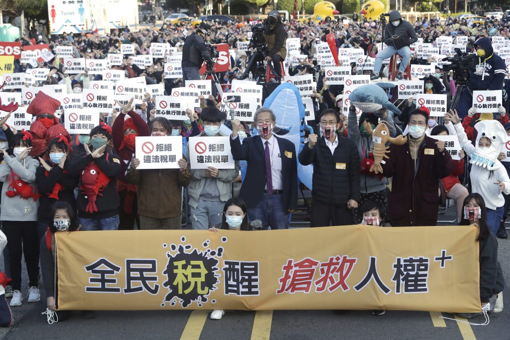 2021年12月19日、総統府(台北)の建物前での抗議活動で、納税者の権利を求める「人権救済に目覚めよ」という横断幕を掲げ、叫ぶデモ参加者ら。(ファイル写真/AP)