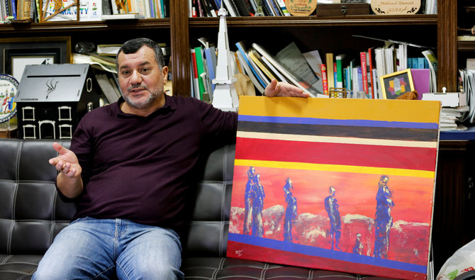 イスラエルに占領されているヨルダン川西岸地区のベツレヘムにあるアイダ難民キャンプの事務所で、自分の絵画を見せるパレスチナ人のアブデルファッタ・アブスルール氏。（ロイター通信）