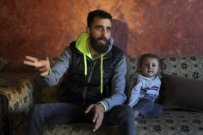 家族と共にヨーロッパに移民しようと試みたザイアド・カレド・ヒルウェ氏（23歳）がレバノン北部の町、トリポリにある両親の家でインタビューに答えている様子。2歳の娘、ジャナちゃんが隣に座っている。2021年12月6日（月）撮影。（AP通信）