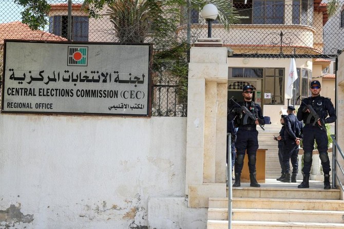 2021年3月20日、ガザ市の中央選挙委員会事務所でパレスチナ人たちが5月の議会選挙の政党リスト登録を開始するなか、警察官たちが監視している。（ロイター）