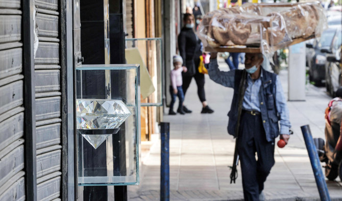 レバノンの首都ベイルート近隣にある人気のブルジュハモウドの市場で、閉店した宝石店の前を通るペイストリーの行商人。2021年12月14日撮影。（AFP）