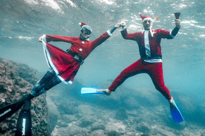 24日にレバノン北部の町バトロウン沖の水中で、サンタクロース衣装を身につけてポーズを撮るフリーダイバー。（AFP）
