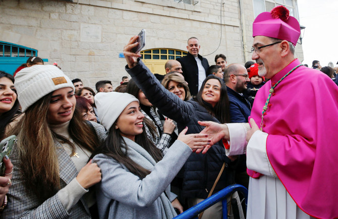 エルサレムのローマカトリック教会大司教ピエールバッティスタ・ピッツァバッラ氏が人々に挨拶した。2021年12月24日、イスラエルが占領するウェストバンクで、ベツレヘムのクリスマス祝祭に参加するために訪れた。（ロイター）