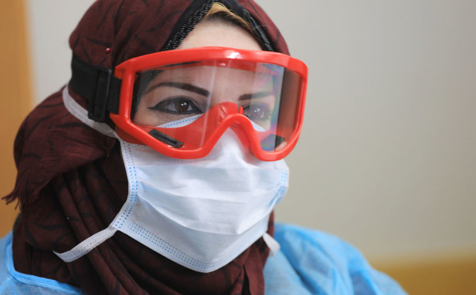 2020年3月18日、ガザ市のアル・シャティ難民キャンプにある国際連合パレスチナ難民救済事業機関の学校で、防護マスクとゴーグルを身に着けたパレスチナの医療従事者の姿が捉えられた。（AFP通信）