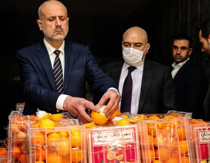 2021年12月29日、カプタゴンの錠剤が入った偽のオレンジを調べるレバノンのバッサン・アル・マウラウィ内相（左）。(AFP通信)
