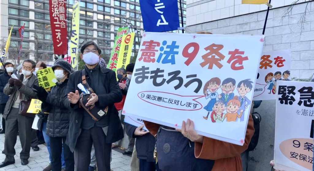 東京の国会議事堂に向かって「とりもどそう!民主主義」などと書かれたプラカードを持つデモ参加者たち。(ANJ/ピエール・ブティエ)