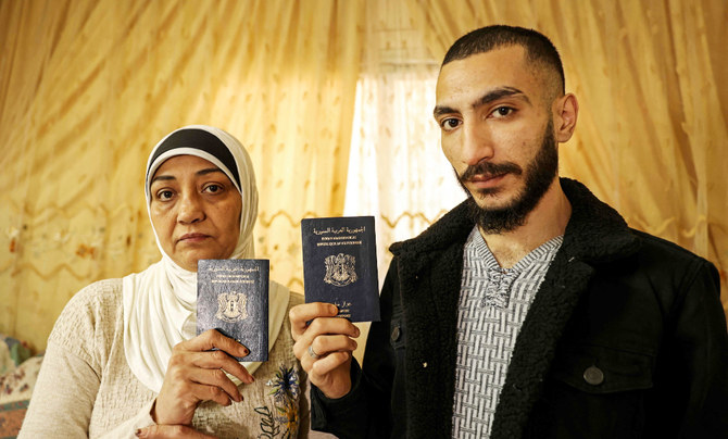 ガザ市の自宅で、期限切れのシリアのパスポートを見せるシリア難民のリナ・ムスタファ・ハッスーン氏と息子のナウラス・ディーブ氏。2021年12月5日撮影。（AFP）