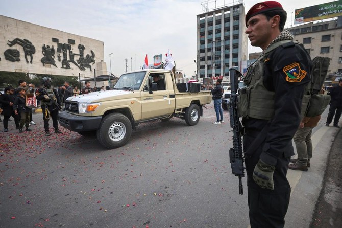 2021年12月29日、バグダッドのタハリール広場で行われた象徴的な意味をもつ葬儀で、元軍事同盟ハシュド・アル・シャアビのイラク治安部隊の隊員が警備に当たる。（ファイル/AFP通信）