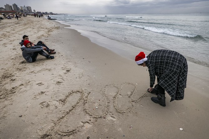 12月31日、1年最後の日没を前にしてガザ市に沿った浜辺の砂に「2022」と暦を記す女性。（AFP）