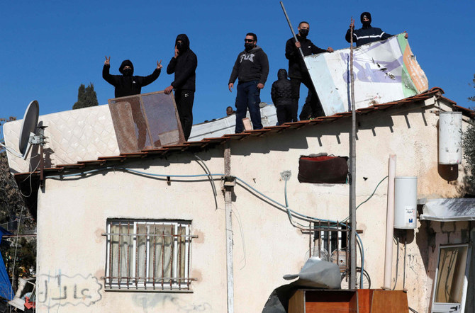 東エルサレムのシェイク・ジャラー地区で、イスラエル警察がパレスチナ人の一家を立ち退かせる準備を進める中、同じ家の屋根の上にガスタンクを用意して佇む男性たち。(1月17日、Ahmad Gharabli/AFP)