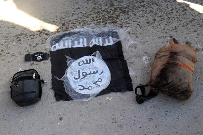 シリア北東部のハサケで、武装集団がグワイラン刑務所を攻撃した後、クルド人主導のシリア民主軍に逮捕された戦闘員から没収したダーイシュの旗とバッグ。(ファイル/AP)