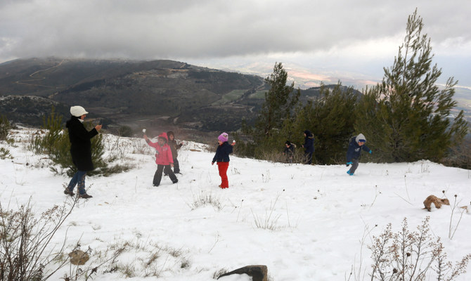 雪で遊ぶ子供達を携帯電話で写真におさめる女性。2022年1月27日、レバノンのフラ村にて。（ロイター）
