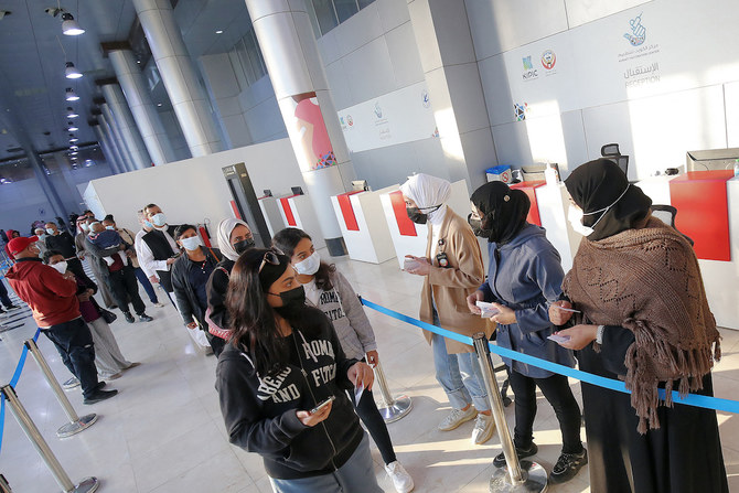 クウェート市のクウェート国際催事場に設けられたワクチン接種会場にCovid-19ワクチンの3回目の接種を受けに来た人々が、接種ブースへと案内されている。2022年1月3日に撮影（写真提供：AFP通信）
