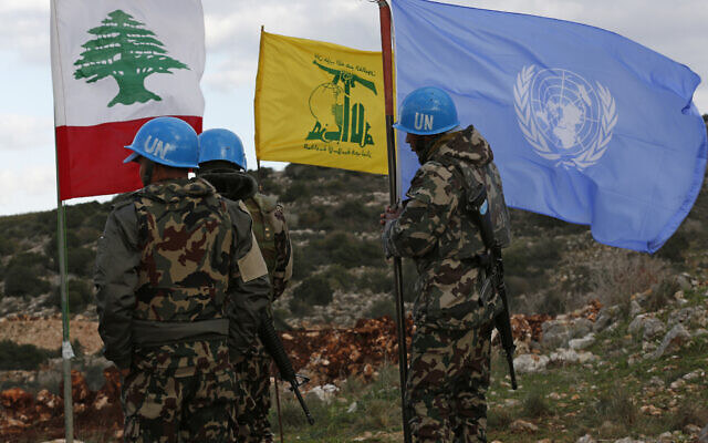 ヒズボラの旗とレバノン国旗の横で、国連の旗を掲げる国連平和維持要員。 (写真:AP)