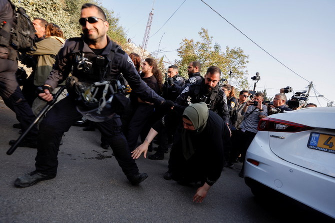 東エルサレムのシェイク・ジャラー地区で抗議活動中のパレスチナ人女性を引っ張るイスラエル治安部隊の隊員＝2022年2月18日（ロイター通信）