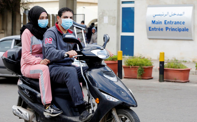 レバノン初のコロナウイルス感染者が隔離されているラフィーク・ハリーリ病院の外で、フェイスマスクをつけながらバイクに乗る人々、2020年2月21日、レバノン、ベイルートにて。（ロイター通信）
