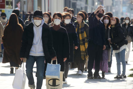 コロナウイルスの蔓延を防ぐためにフェイスマスクを着用している人々は、2022年2月15日火曜日に通りを歩きます。（AP）