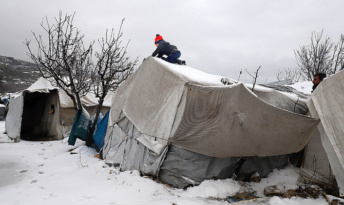 先月、国内避難民キャンプのテントに積もった雪を除去する幼い少年。シリア北西部のジスル・アッシュグール市近郊にて。(AFP/資料)