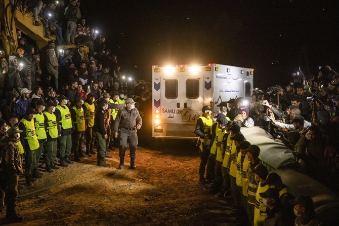 2月1日夜、5歳のラヤン君の遺体を載せた救急車が、転落した井戸のある現場を後にする中、列を成して見物人を抑える治安部隊。（AFP）